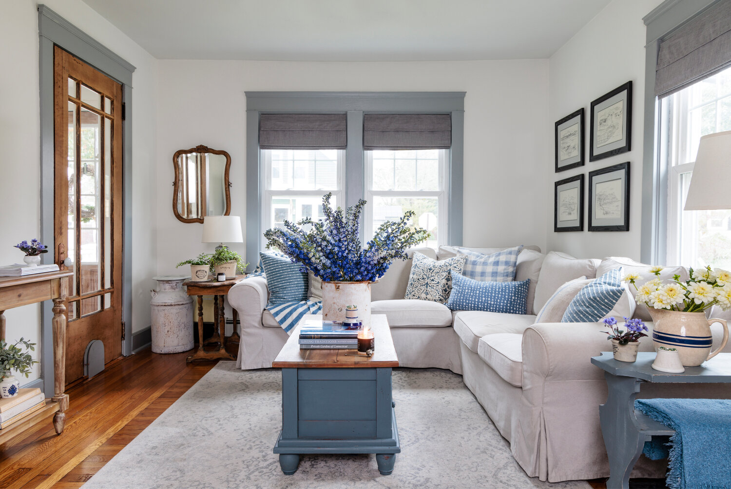 In the cozy living room, blue accents rest against 
a white backdrop. A narrow coffee table and slender credenza/sideboard balance the ample sofa.
