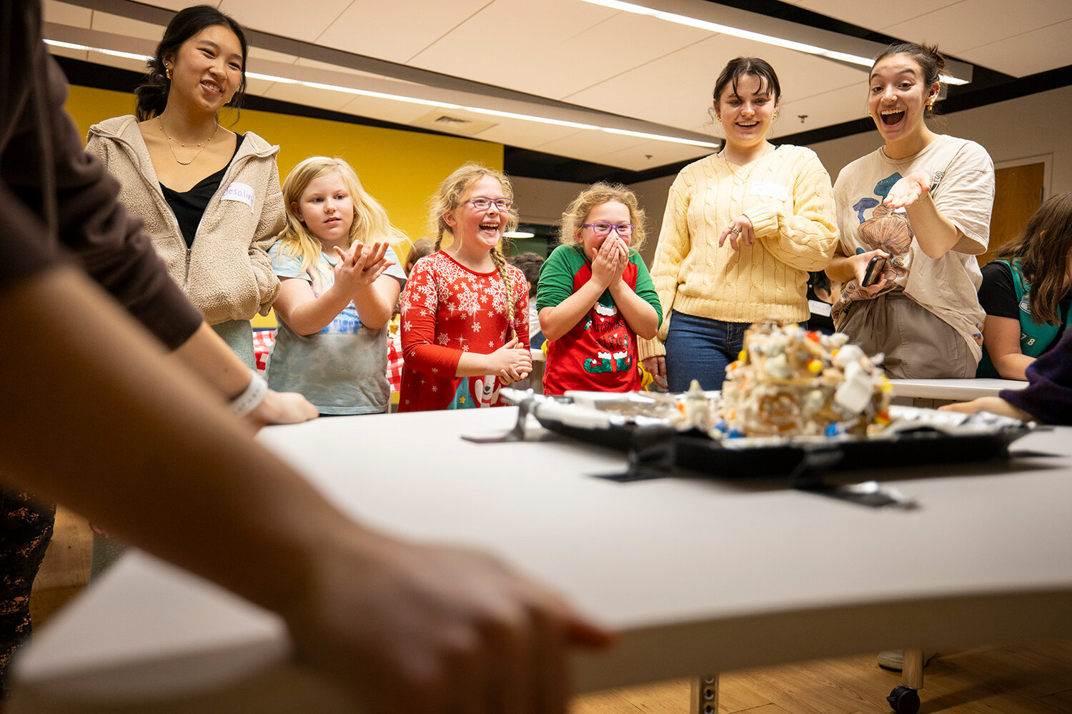 Photos of Brown University Society of Women Engineers members working with Girls Scouts at the Girl Scouts of Southeastern New England Council Headquarters in teams to build a gingerbread house that can withstand a shake test